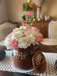 a vase filled with flowers sitting on top of a table next to a cookie jar