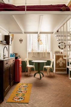 a kitchen and dining area with stairs leading up to the loft bed in this small apartment