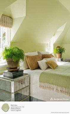 a bedroom with a bed, nightstand and potted plant in the corner on top of it