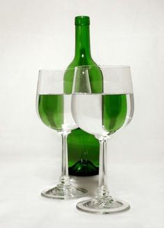 two empty wine glasses next to a green bottle