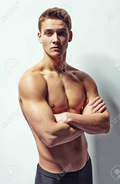 a man with his arms crossed posing for a photo in front of a white wall