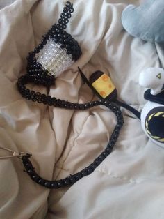 two stuffed animals are laying on a bed with white sheets and black beaded headbands