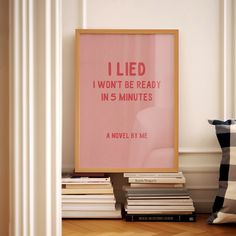 a pink poster sitting on top of a wooden floor next to a pile of books