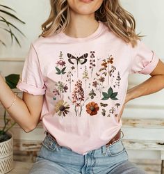 a woman wearing a pink t - shirt with flowers and butterflies on it