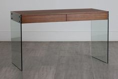 a glass desk with a wooden top and drawers on the bottom, against a white wall