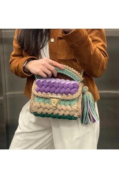 a woman is holding a woven purse