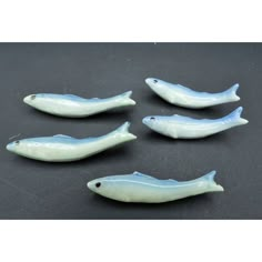 five small plastic fish on a black surface with white trimmings and blue tips