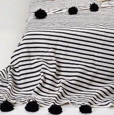 a black and white striped bed spread with pom - poms