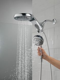 a person is holding the shower head in their hand and it's spraying water