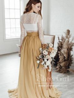 a woman standing in a room wearing a dress with sheer sleeves and a long skirt