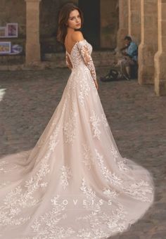 a woman in a wedding dress is standing on the street with her back to the camera