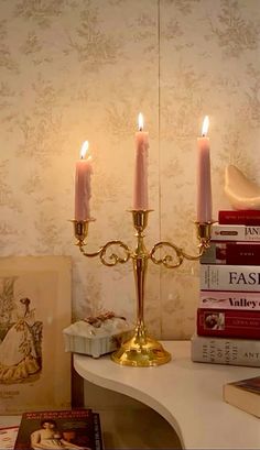 three candles are lit on a table with books