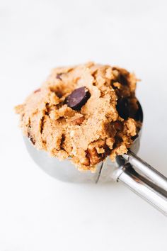 an oatmeal cookie with chocolate chips is in a metal bowl on a white surface