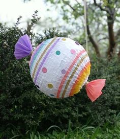 a paper lantern hanging from a tree in the woods with colorful stripes and polka dots on it