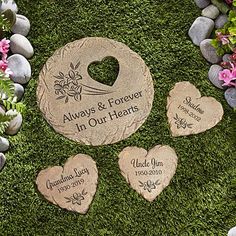 four heart shaped stepping stones in the grass with names and date engraved on one stone