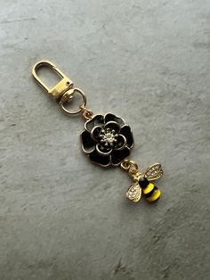 a keychain with a bee and flower charm attached to it on a stone surface