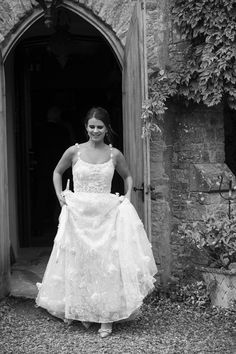 a woman in a wedding dress standing outside an old building with ivy growing on the walls