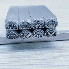 four metal objects sitting on top of a wooden table next to each other, one is shaped like an elephant and the other has five smaller elephants