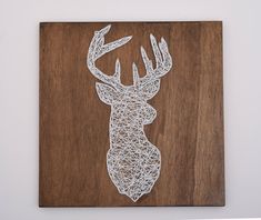 a string art deer head mounted on a wooden plaque with white paint and wood grain