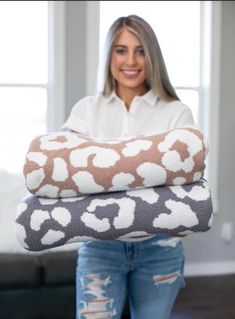 a woman holding two blankets in her hands