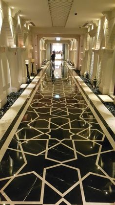 a long hallway with black and white tiles on the floor in an upscale hotel lobby