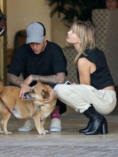 a man kneeling down next to a woman petting a dog