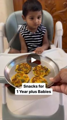 a child sitting in a highchair with food on the plate and hands holding it