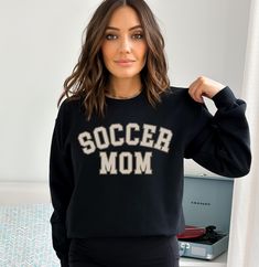 Are you the ultimate Soccer Mom, cheering on your superstar player from the sidelines? Celebrate your devotion to the beautiful game with our custom "Soccer Mom" sweatshirt, where style meets soccer spirit! This cozy and fashionable sweatshirt is perfect for chilly match days or casual outings, and it's personalized just for you. 🌟 Key Features 🌟 ✨ "Soccer Mom" Front Design: Let everyone know you're the proudest soccer mom with our eye-catching "Soccer Mom" text on the front. It's more than ju Collegiate Black Sweatshirt For Football Season, Black Football Season Sweatshirt With Team Name, Black Sweatshirt With Team Name For Football Season, Black Sweatshirt With Football Team Name, Black College Sweatshirt For Football Season, Black Football Season Sweatshirt, Black School Spirit Sweatshirt For Sports, Black Fan Apparel Sweatshirt For Football Season, Black Sports Fan Sweatshirt For Sports Season