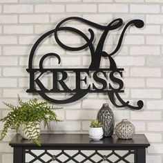 a metal sign that says kresss on top of a table with two vases