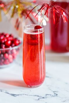 a glass filled with liquid sitting on top of a table next to some cranberries