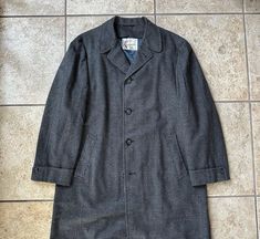 "Here is a vintage sack overcoat by \"Rexvelo\" for \"Shillito's\" of Cincinatti, OH, that can be dated to the 1950s. There is no size tag, but it could fit sizes 40 through 42 Regular, depending on preferred overcoat fit; still, please use the measurements provided as a reference.  Union-made in the USA of what is assuredly 100% tweed wool, it has a houndstooth check of gray & charcoal along with a red windowpane plaid. The quality is beyond superb with full canvassing, piping on the inner seam Vintage Wool Long Coat, Retro Tweed Outerwear With Notch Lapel, Retro Tailored Tweed Outerwear, Tailored Retro Tweed Outerwear, Retro Tweed Outerwear For Business, Vintage Houndstooth Outerwear With Notch Lapel, Fitted Vintage Outerwear With Houndstooth Pattern, Vintage Houndstooth Outerwear, Vintage Single-breasted Tweed Outerwear