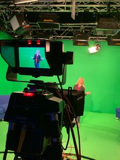 a camera set up in front of a green screen with a woman on the television