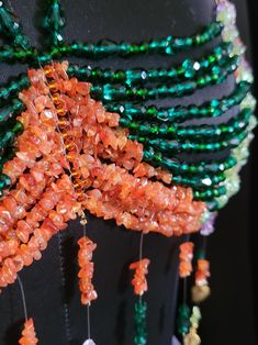 an orange and green beaded dress with beads hanging from it's back end