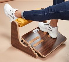 a person standing on top of a wooden chair with their feet on a stool that is attached to the legrests