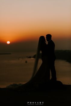 a bride and groom are silhouetted against the sunset