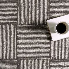 a cup of coffee sitting on top of a white and black checkered floor mat