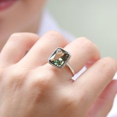 a close up of a person wearing a ring with a green stone in the middle