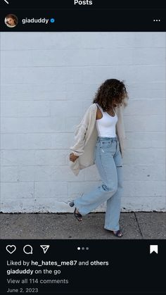 a woman leaning against a white brick wall