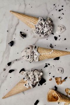 three scoops of ice cream sitting on top of a marble counter next to cookies and oreos