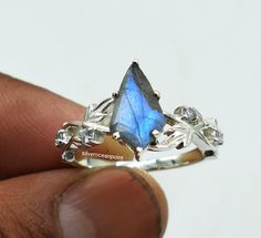 a hand holding a ring with a blue and white stone in it's center