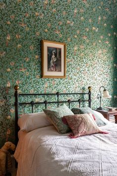 a bed in a bedroom with green wallpaper and white bedspread on it