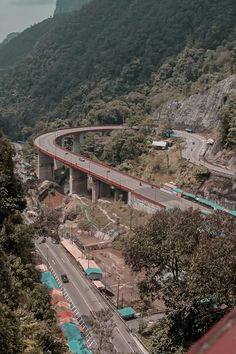 an aerial view of a highway and bridge in the middle of a mountainous area with trees on both sides