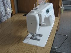 a white sewing machine sitting on top of a wooden table