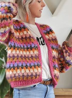 a woman wearing a colorful knitted cardigan holding a cell phone in her right hand