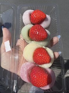 a plastic container filled with different types of donuts and strawberries on top of each other