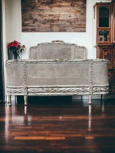 a white wicker bed sitting on top of a hard wood floor next to a wall