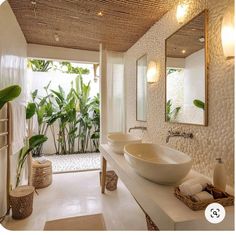 a bathroom with two sinks, mirrors and plants in the shower area on either side of the bathtub