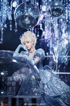 a woman in a blue dress is posing for a photo with disco balls hanging from the ceiling