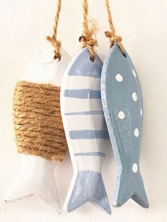 two ceramic fish hanging from twine on a white wall next to a roped burlock