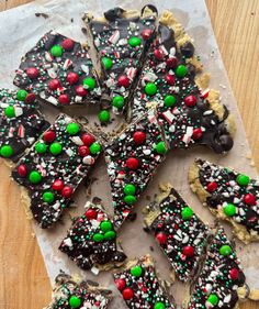 a table topped with lots of chocolate and candy covered cookies on top of parchment paper